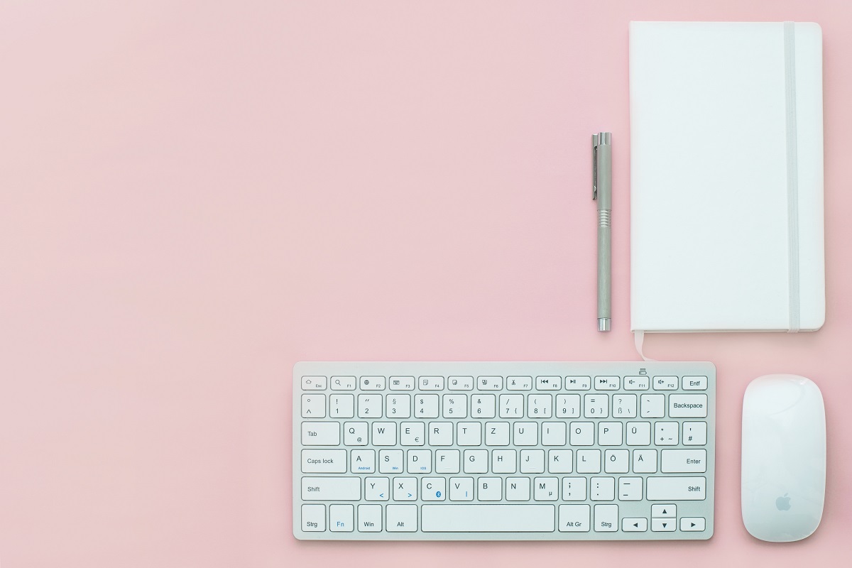 teclado, mouse, caneta e caderno de anotações organizados em cima de uma mesa