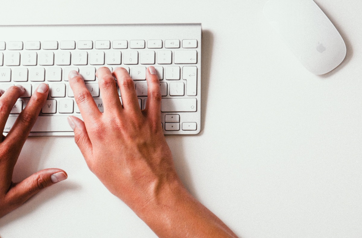 Pessoa digitando em um teclado branco