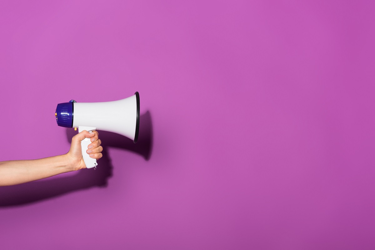 Mão segurando megafone em um fundo roxo