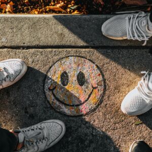 Duas pessoas de frente uma para outra em uma calçada com desenho de uma carinha sorrindo