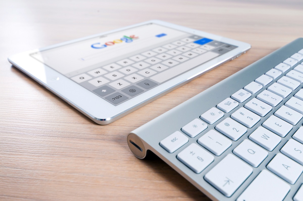 Tablet com a página inicial do google aberta e teclado em cima de uma mesa de madeira