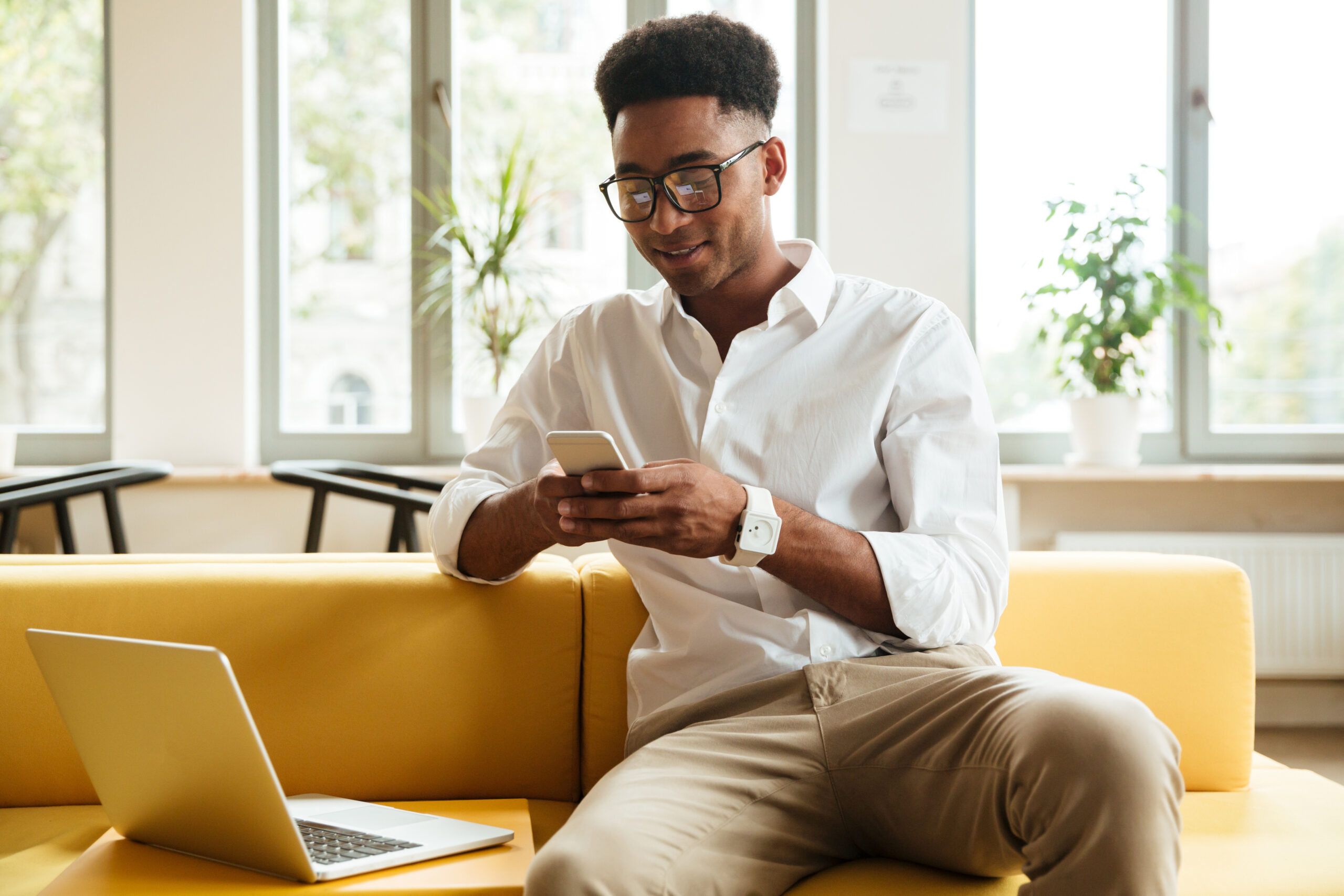 homem negro sorrindo enquanto utiliza chat-commerce no celular